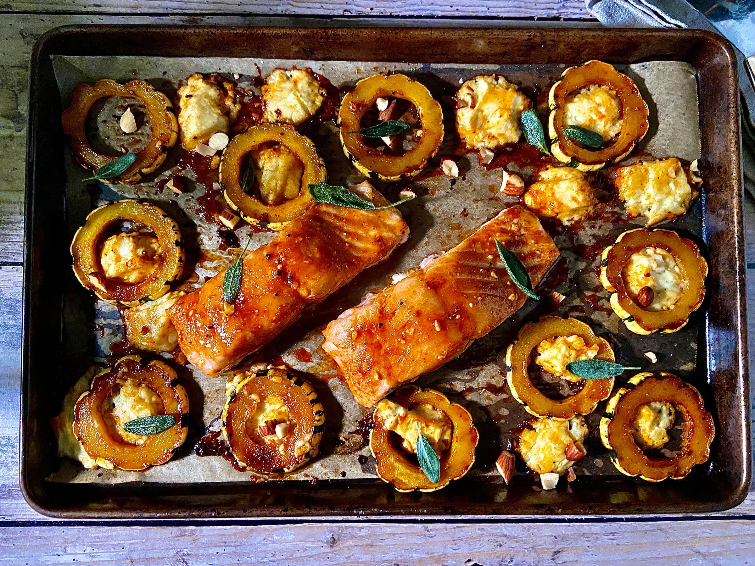 baking sheet with salmon, squash, cheese, and herbs