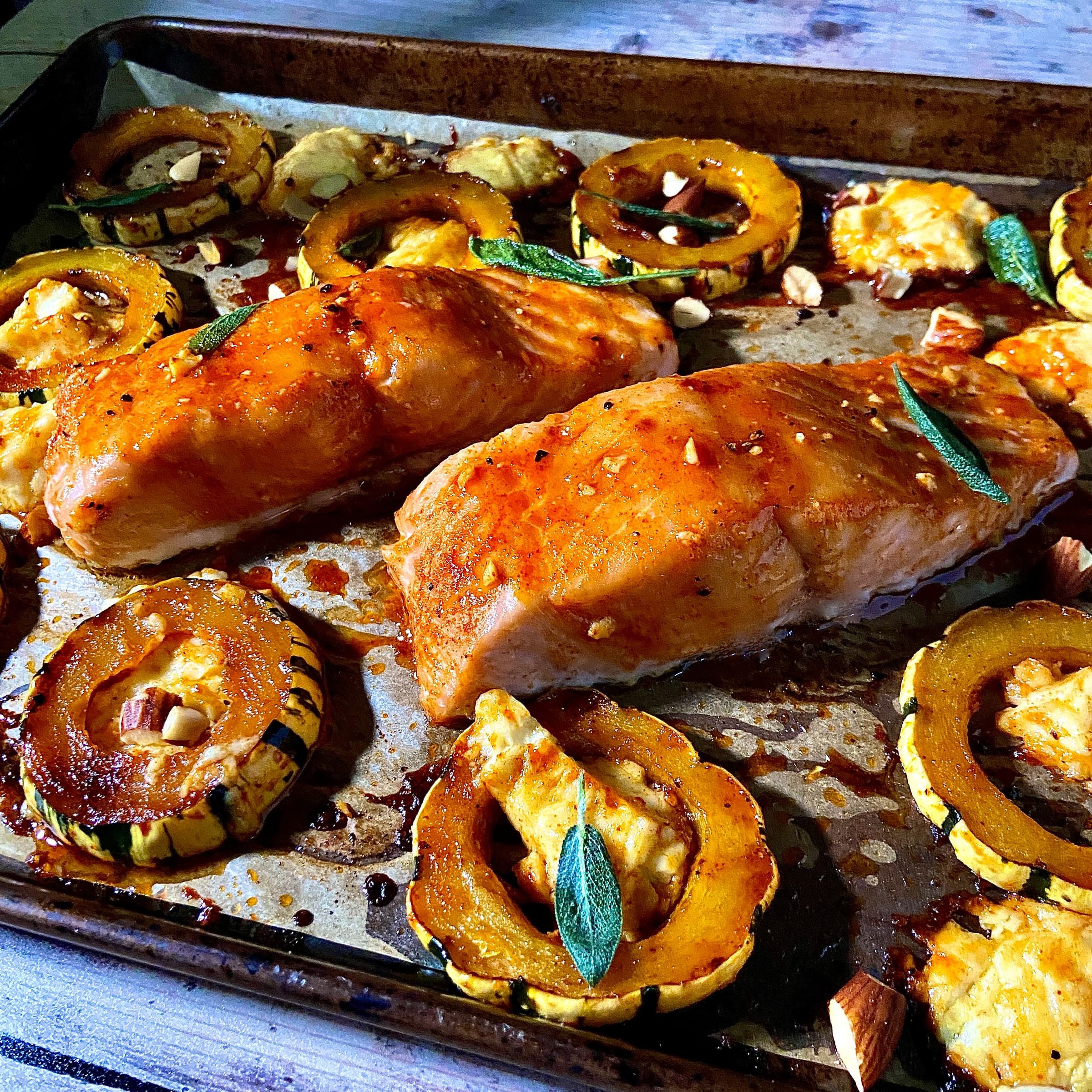 baking sheet with salmon, squash, cheese, and herbs