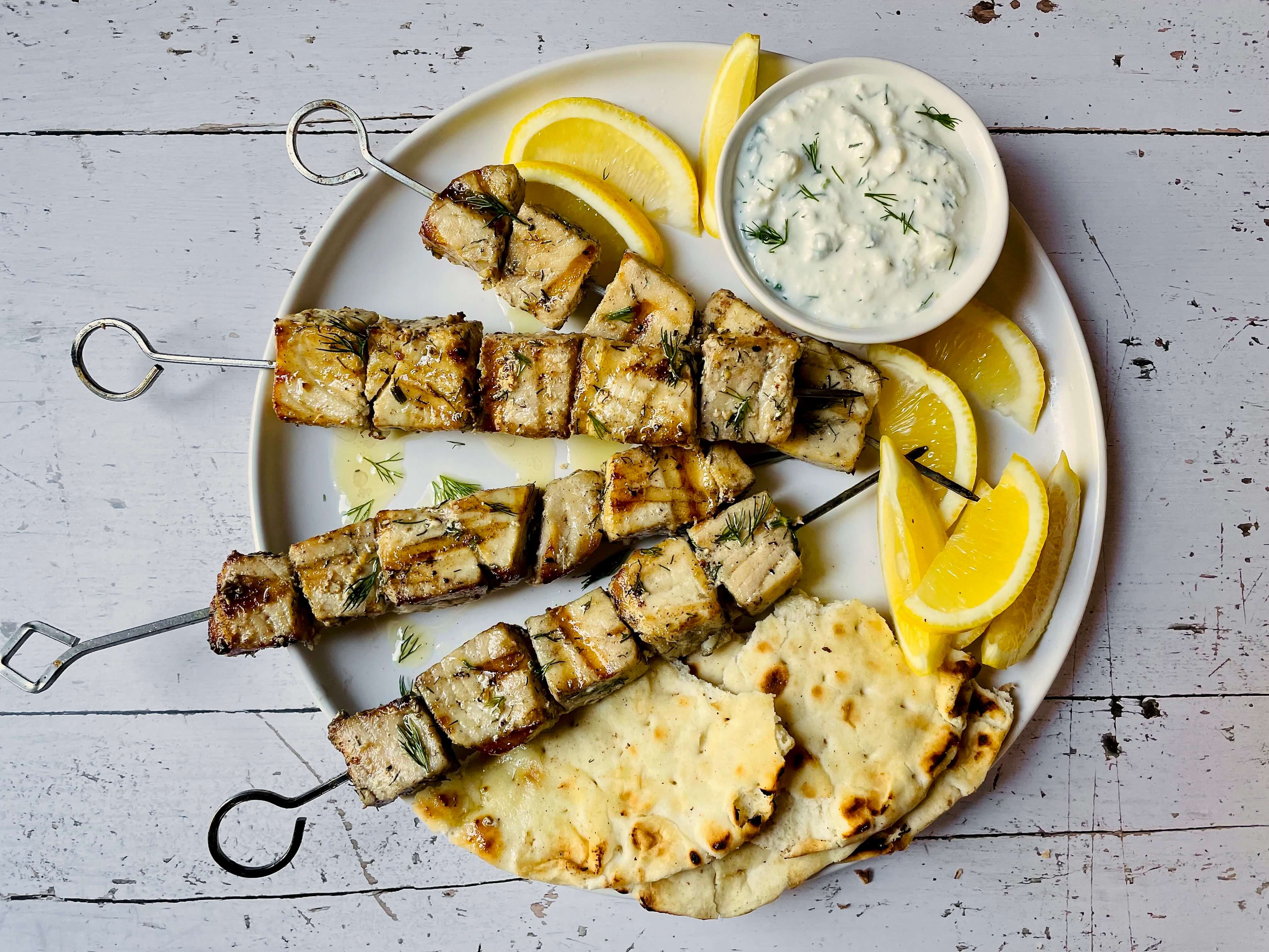 fish kabobs with lemon, pita, and yogurt sauce