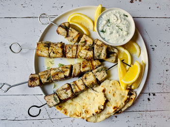 fish kabobs with lemon, pita, and yogurt sauce