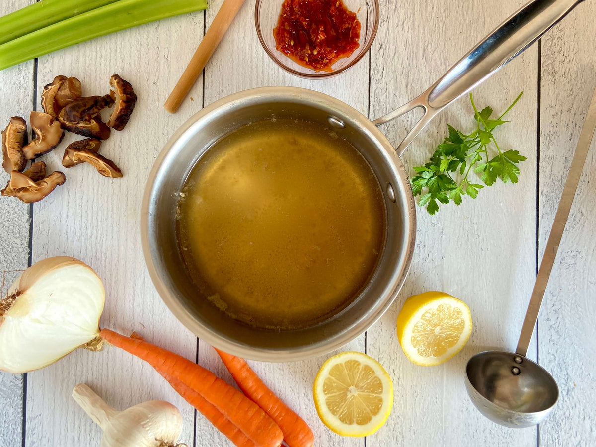 pot of soup with vegetables on a board